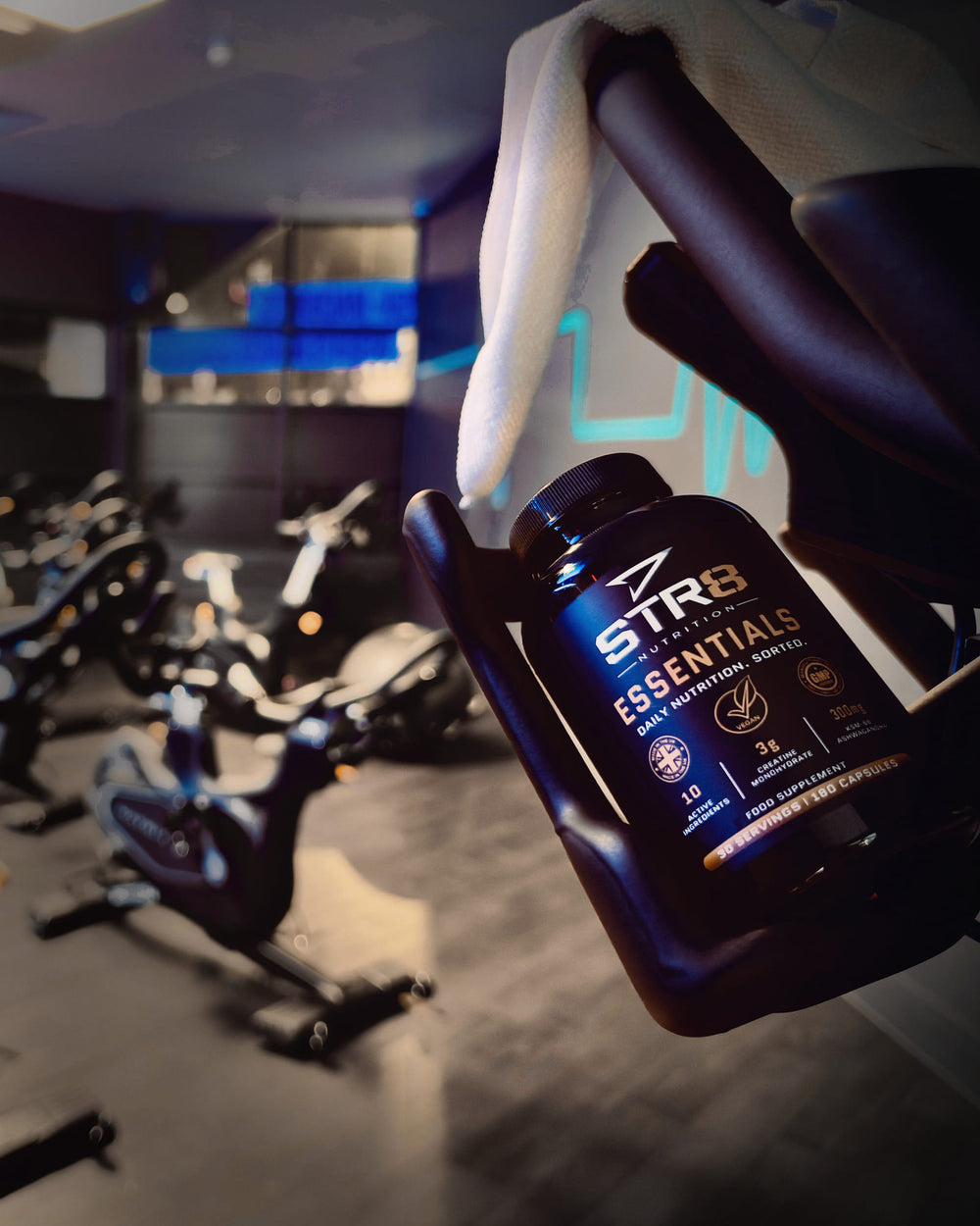 Essentials bottle in a spin bike cup holder, studio bikes behind